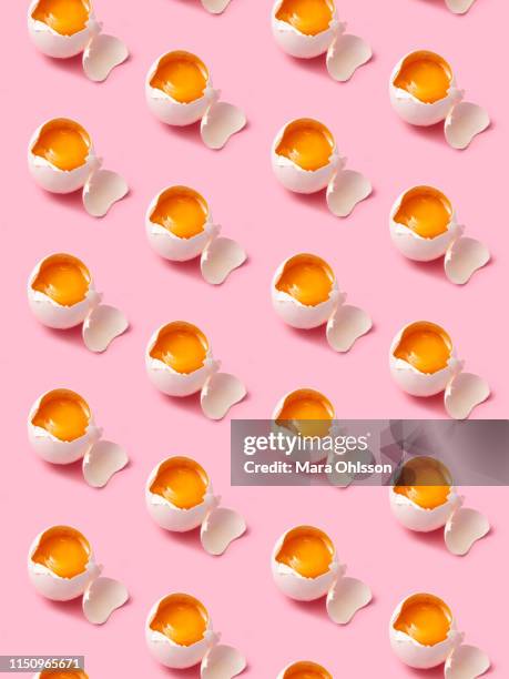 broken eggs arranged in rows on pink background - easter pattern stockfoto's en -beelden