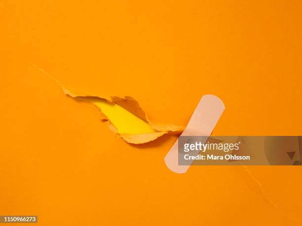 first aid adhesive plaster on torn orange paper - 臨時 個照片及圖片檔