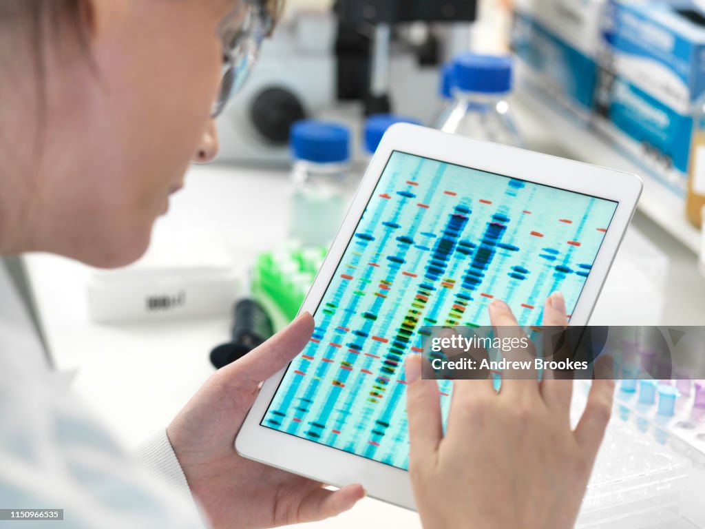 Female scientist examining DNA sequence results on digital tablet in laboratory