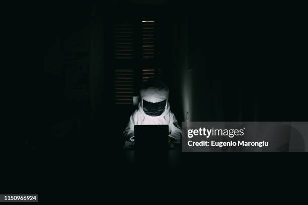 astronaut using laptop in dark room - astronaut portrait stock-fotos und bilder