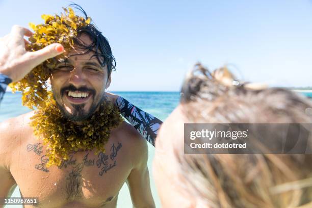 woman wrapping seaweed around man's neck in sea, pagudpud, ilocos norte, philippines - pechos de mujer playa fotografías e imágenes de stock