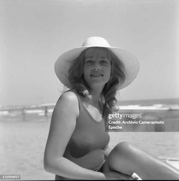 French actress Jeanne Moreau, portrayed wearing a swimming suit and a wide-brimmed hat, the seashore and some people in the background, Lido beach,...