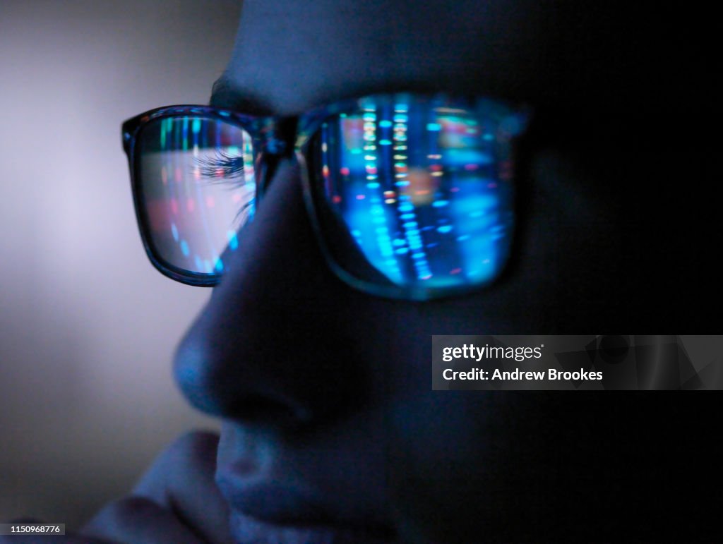 Genetic research, computer screen reflection in spectacles of DNA profile, close up of face