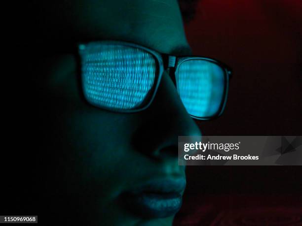 cyber crime, reflection in spectacles of virus hacking a computer, close up of face - cyber harcèlement photos et images de collection
