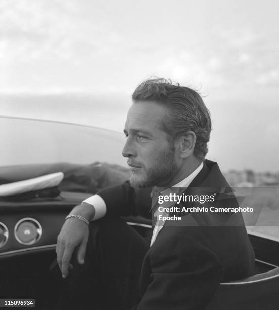 American actor Paul Newman, wearing a tuxedo and a bow tie, portrayed during a trip on a water taxi, a sailor cap on the dashboard, Venice 1963.