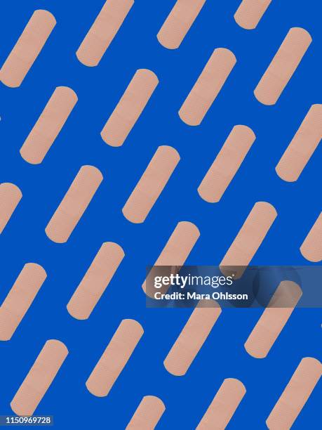 first aid adhesive plasters in diagonal pattern on blue background - pleister stockfoto's en -beelden