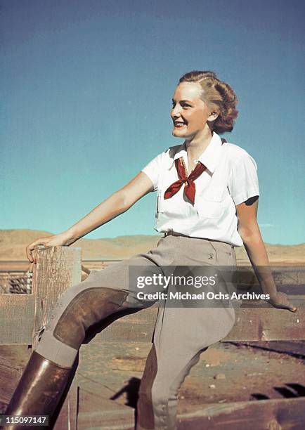 Model sitting on a fence wearing jodhpurs and riding boots in the 1930's.