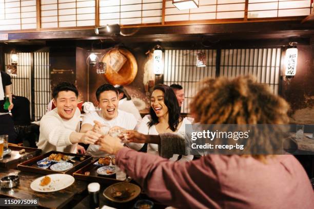 gruppo di viaggiatori di razza mista che si divertono a bere alcolici in un pub in stile giapponese - japanese restaurant foto e immagini stock