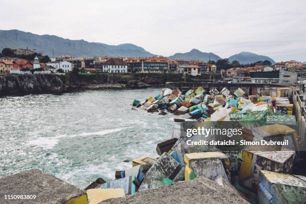 llanes harbor painted concrete blocks on atlantic coast of spain - llanes stock-fotos und bilder