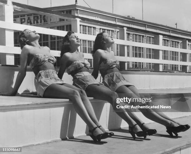 Janice Cooper, Marilyn Connor and Gloria Ellexson wearing bathing suits made from World War 2 Air Force escape maps, given to them by their...