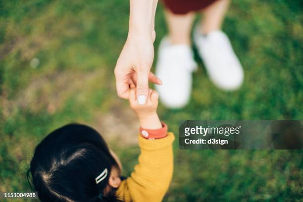 close up of mother holding hands of cute little daughter relaxing in the park on a lovely day - kid hand raised stock pictures, royalty-free photos & images