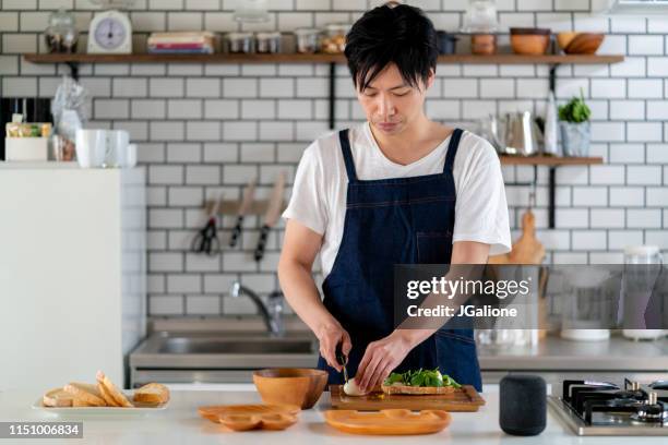young adult male cooking at home alone - preparing food stock pictures, royalty-free photos & images