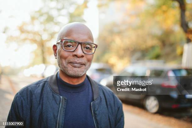 portrait of smiling senior man standing on road - males stock pictures, royalty-free photos & images