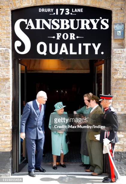 Queen Elizabeth II talks to actors in period costume as she visits a replica of one of the original Sainsbury's stores in Covent Garden to mark the...