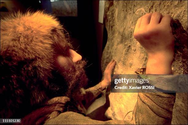 Prehistorical museum in Quinson, France on May 29, 2001 - Paleolithic period , a scene showing a Neanderthal man engraving a rock wall using a...