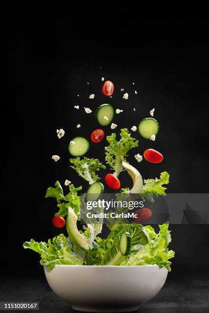 ingredientes de ensalada volando por el aire, aterrizando en un tazón - cucumber leaves fotografías e imágenes de stock