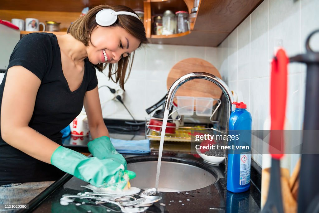 Woman cleaning kitchen, washing dishes