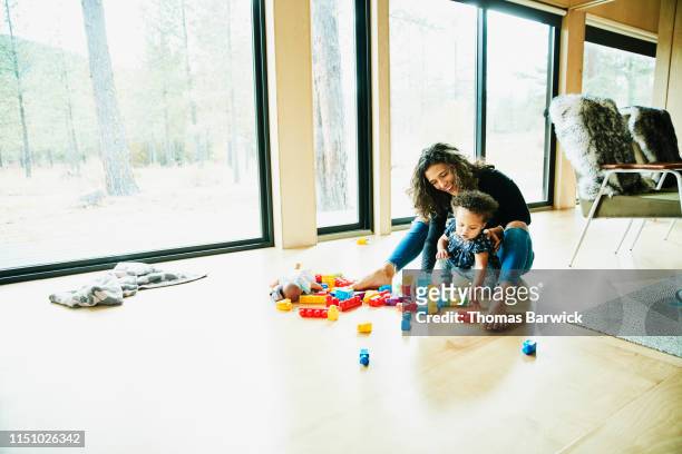 Smiling mother playing with toddler daughter on floor on living room