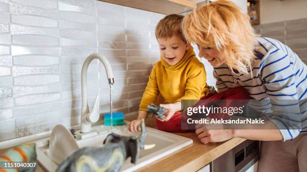 mom and son washing dishes and toys together - toy animal stock pictures, royalty-free photos & images