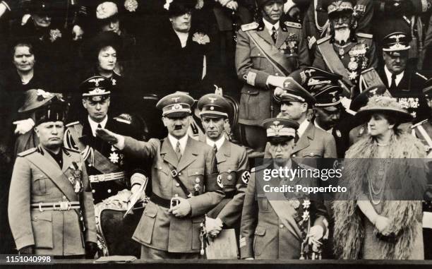 Benito Mussolini of Italy, German chancellor Adolf Hitler giving the Nazi salute, and Victor Emmanuel II with his Queen, Elena of Montenegro, in Rome...