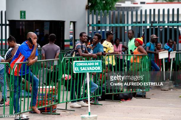 Migrants of different nationalities queue outside the Mexican National Institute of Migration, near a sign marking the line for the Salvadorean...