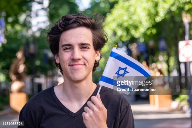 joven sonriente agitando la bandera israelí - israeli ethnicity fotografías e imágenes de stock