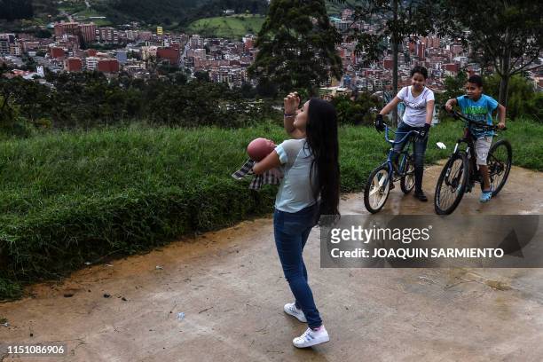 Teenage student Susan Ortegon, takes care of a baby robot as she walks around her neighborhood in Caldas, Antioquia's department, Colombia on May 19,...