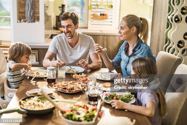 famille heureuse parlant pendant l’heure de déjeuner dans la salle à manger. - quatre personnes photos et images de collection