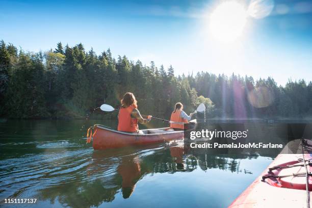 pov, sunlit kayak de verano con mujeres piragüismo en wilderness inlet - canoa fotografías e imágenes de stock