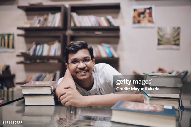 portrait of teenage boy in the library - indian boy portrait stock pictures, royalty-free photos & images