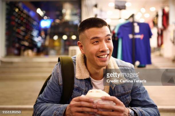 man eating a chinese steamed bun on the street - vietnamese street food stock-fotos und bilder