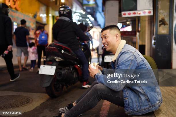 man eating a chinese steamed bun on the street - vietnamese street food stock-fotos und bilder