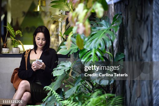 Chinese woman using a smart phone in an urban garden Chinese woman using a smart phone in an urban garden