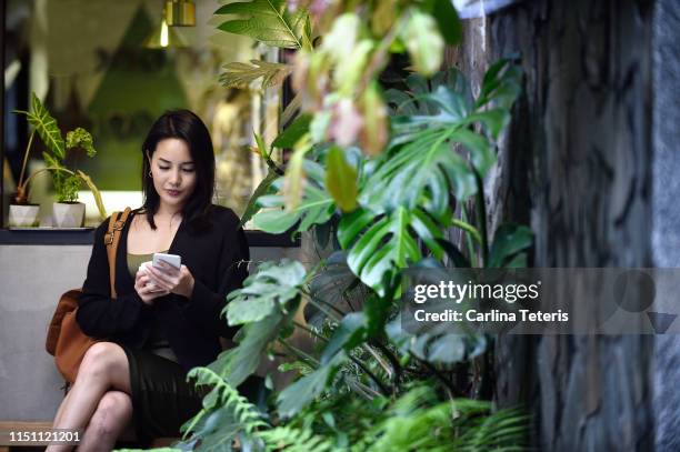 chinese woman using a smart phone in an urban garden - taipei business stock pictures, royalty-free photos & images