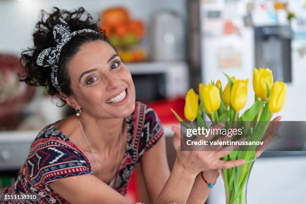 lovely woman arranging yellow tulips bunch in vase - flower presents stock pictures, royalty-free photos & images