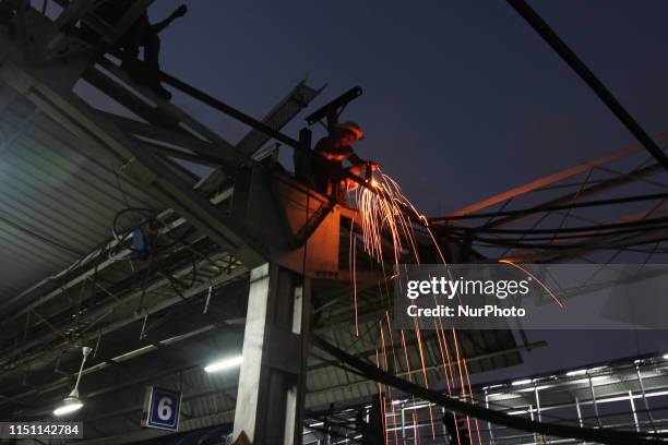 Worker welds as he stands on the metal frame at a railway station in Mumbai, India on 20 June 2019.