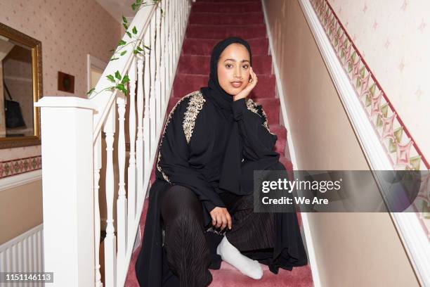 portrait of young muslim woman sitting on carpeted stairs - camera flash stock pictures, royalty-free photos & images