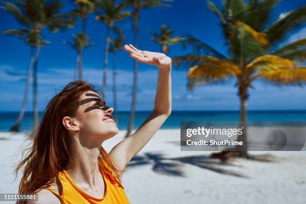 woman covers her face from the sun with her hand on the beach - tanned body stock pictures, royalty-free photos & images