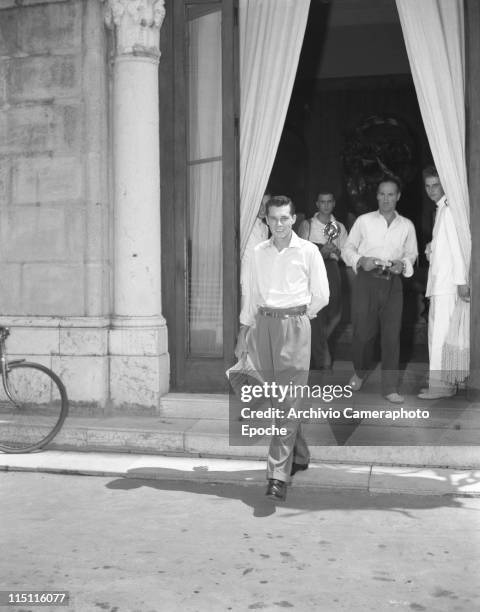 Heir Conrad 'Nicky' Hilton, first husband of Elizabeth Taylor, walking out of a building, followed by photographers, Venice, 1950.