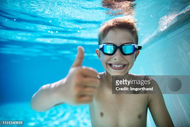kleiner junge im pool zeigt daumen hoch - water cooler stock-fotos und bilder