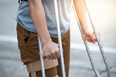Disabled woman with crutches or walking stick or knee support standing in back side,half body.