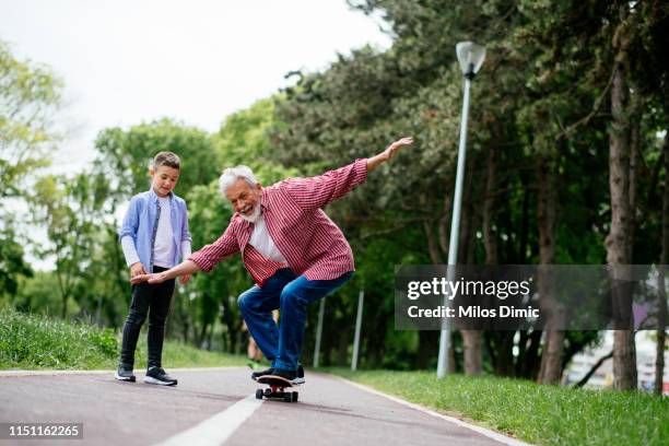 little boy trying skateboard - senior skateboard stock pictures, royalty-free photos & images