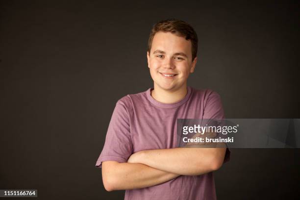 studio portret van een 18-jarige man in een paars t-shirt op een zwarte achtergrond - 18 year stockfoto's en -beelden