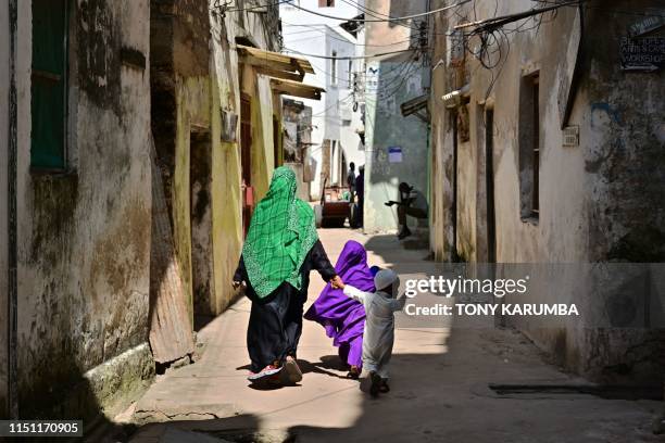 This picture taken on June 19, 2019 shows people walking along narrow streets at Kenya's resort town of Lamu, a UNESCO world heritage site that is...