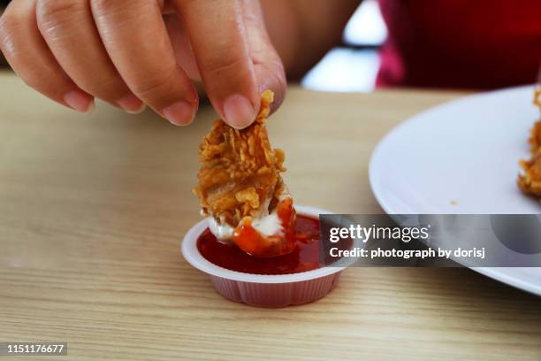 woman hand dipping fried chicken fillet into sauce - dipping sauce stock-fotos und bilder