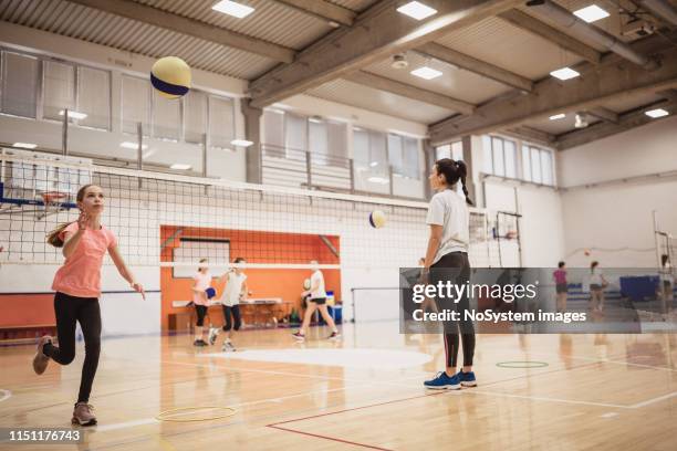 female volleyball team exercising indoors on volleyball court - candid volleyball stock pictures, royalty-free photos & images