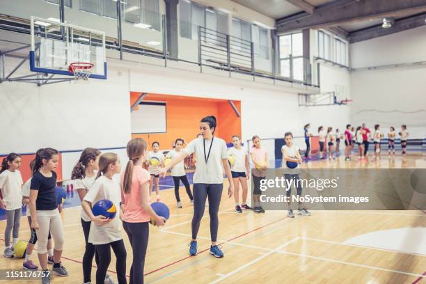 volleyball-trainer im gespräch mit einer gruppe von mädchen über das training - hallenvolleyball stock-fotos und bilder