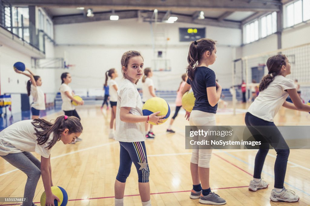 Équipe féminine de volley-ball s'exerçant à l'intérieur sur le terrain de volley-ball