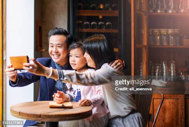 asiatische familie nimmt selfie in einem café - asian family cafe stock-fotos und bilder
