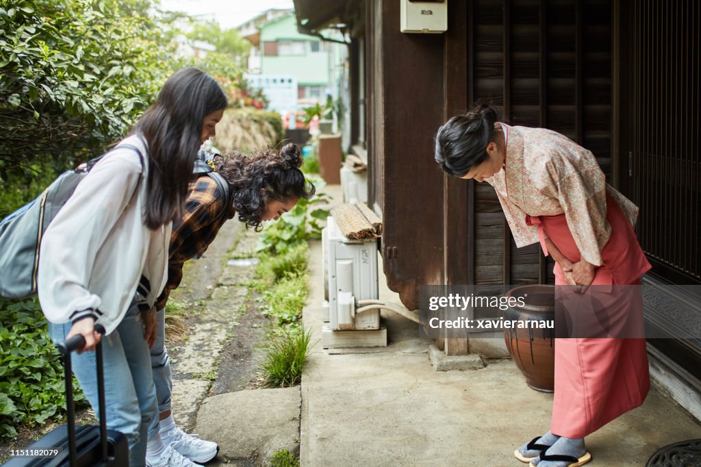 Landlady greeting female guests outside ryokan